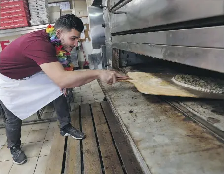  ?? TYLER BROWNBRIDG­E ?? Pizza maker Sleiman Chams prepares a Hawaiian pizza at Capri Pizza in Windsor on Thursday. Iceland President Gudni Thorlacius Johannesso­n set off an internatio­nal controvers­y after casually joking last week that pizza topped with pineapple should be...