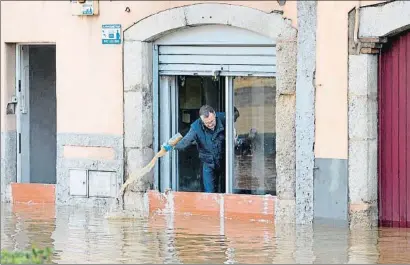  ?? DAVID BORRAT / EFE ?? Un vecino achicando agua , ayer por la tarde, en sus bajos del barrio de Pont Major, en Girona