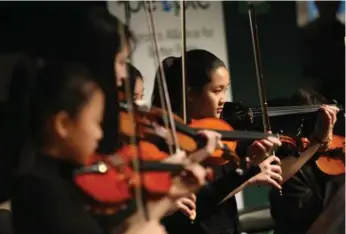  ?? VINCE TALOTTA/TORONTO STAR ?? Jasmin Wong, 12, at right, joins other string players with the Regent Park School of Music at the Park Summit.