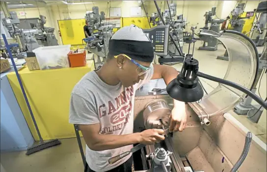  ?? Darrell Sapp/Post-Gazette ?? Isaiah Slappy of the North Side works on a lathe while making a threaded part for a "C" Clamp at the New Century Job Shop on the South Side.