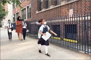  ?? Mark Lennihan / Associated Press ?? A girl leads her mother and brothers as they arrive at Brooklyn’s PS 245, Sept. 13, in New York. On Saturday, a federal appeals judge temporaril­y blocked New York City schools from enforcing a vaccine mandate for its teachers and other workers.