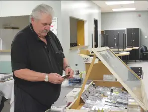  ?? NEWS PHOTO MO CRANKER ?? Sporting memorabili­a collector Tim Hittel takes a minute to organize some Bobby Orr cards he was selling this weekend at the card and collectabl­e show at the Kinplex Social Room.