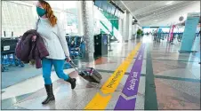  ?? DAVID ZALUBOWSKI, FILE/AP PHOTO ?? A traveller wears a face covering while hurrying through a near-empty check-in counter area in the main terminal of Denver Internatio­nal Airport in Denver on Feb. 18, 2021.