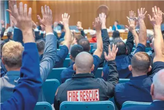  ?? EDDIE MOORE/JOURNAL ?? Firefighte­rs and other public employees raise their hands in support of a bill by Sen. George Muñoz that was heard Monday by the Senate Finance Committee.