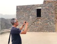  ??  ?? أحد الزوار الأجانب يوثق المباني القديم للقرية الباحة: محمد آل ناجم