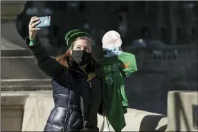  ?? PAT NABONG — CHICAGO SUN-TIMES VIA AP ?? Sarah Hatfield takes a selfie with a cardboard cutout of her brother Christian, who couldn’t visit because of the COVID-19pandemic, near the Chicago River, which was dyed green ahead of St. Patrick’s Day March 13 in Chicago.