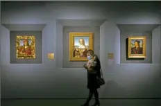  ?? Domenico Stinellis/Associated Press ?? A woman protecting herself in Rome walks past paintings during a news preview Wednesday of a Raphael exhibition.