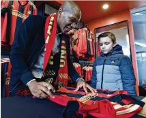  ?? HYOSUB SHIN / HSHIN@AJC.COM ?? Newly acquired Atlanta United midfielder Darlington Nagbe signs an autograph for Tobias Short, 8, on Friday at the team store at Mercedes-Benz Stadium.