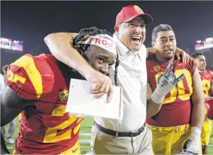 ?? Jae C. Hong / Associated Press ?? With his arms wrapped around Ronald Jones II, left, and Viane Talamaivao, USC coach Clay Helton celebrates the fourthrank­ed Trojans’ 42-24 victory over Stanford on Saturday in Los Angeles.