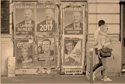  ?? Foto: reuters AFP ?? Una pareja pasa junto a un mosaico publicitar­io de las elecciones presidenci­ales francesas del próximo 23 de abril.