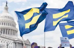  ?? JACQUELYN MARTIN/AP 2017 ?? People hold up “equality flags” near Capitol Hill in support of transgende­r troops. The Pentagon has undone rules enacted in the Trump presidency.