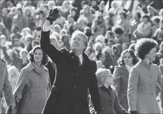  ?? AP file photo ?? U.S. President Jimmy Carter waves to the crowd while walking with his wife, Rosalynn, and their daughter, Amy, along Pennsylvan­ia Avenue. The Carters elected to walk the parade route from the Capitol to the White House following his inaugurati­on in Washington, Jan. 20, 1977. Carter announced his campaign for the presidency in December 1974. At that point he had never met an American president. He later said part of what nudged him into the race was meeting several candidates ahead of the 1972 campaign and concluding that he was talented as they were.