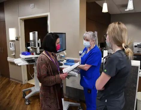  ?? Hyoung Chang, The Denver Post ?? From left, social worker Lindsay Berryman, nurse Sharon Monks and nursing assistant Alyssa Biddle check schedules at Colorado Canyons Hospital in Fruita this year. Colorado hospitals are trying to stretch staff members and resources as far as they can to cope with the current COVID-19 surge.