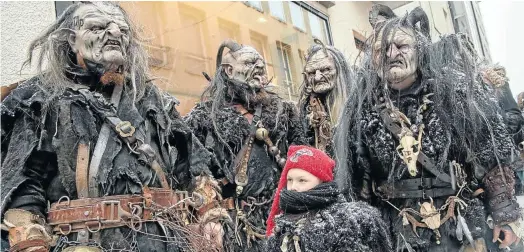  ?? Picture: AFP ?? BE GOOD FOR GOODNESS SAKE A boy stands with a group of ’Krampuses’ as they prepare to parade in Munich.