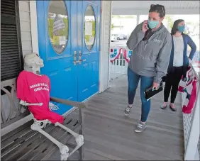  ?? SARAH GORDON/THE DAY ?? Katie Baldwin, supervisor of regulated facilities and housing for Ledge Light Health District, reads a shirt on a skeleton that reads “Make Haircuts Great Again,” as she and First Selectwoma­n Danielle Chesebroug­h wait for owner Cat Thibodeau to open the door Wednesday at Modern Barber in Pawcatuck. The shop reopened in defiance of orders from Gov. Ned Lamont to stay closed.