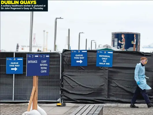  ??  ?? DUBLIN QUAYS A solitary healthcare worker is pictured at Sir John Rogerson’s Quay on Thursday