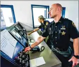  ?? NICK GRAHAM / STAFF ?? Butler County Sheriff’s Office correction­s officers Waylon Thomas and Hannah McCarthy stand in the control room of the old Butler County Court Street Jail.