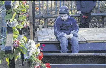  ?? DMITRY LOVETSKY / AP ?? Mikhail, the grandson of one of the plane crash victims, Nina Lushchenko, sits at her grave during her funeral in the village of Sitnya, Russia, on Thursday. All 224 aboard the Metrojet Airbus were killed when it crashed over the Sinai Peninsula a week...