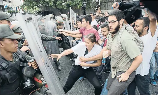  ?? CARLOS BECERRA / BLOOMBERG ?? Un grup d’estudiants s’enfronten a agents de la guàrdia nacional durant una protesta antichavis­ta a Caracas