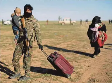  ?? REUTERS PIC ?? A fighter from Syrian Democratic Forces helping a woman to evacuate near the village of Baghouz in Deir Al Zor province on Friday.