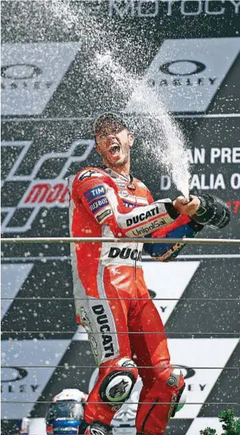  ??  ?? Dovizioso festeggia la vittoria al Gran Premio d’Italia che si è svolto a giugno sul circuito del Mugello. A destra, il pilota mentre prepara la strategia con il suo team. Sotto, la sua Ducati nei box