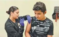  ??  ?? Nurse Alondra Guerrero gives Johnathan Fabiola a shot during the immunizati­on clinic and backpack giveaway.