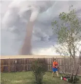  ??  ?? Theunis Wessels mows his lawn on Friday at his home in Three Hills, Alta., as a tornado is seen in the background.