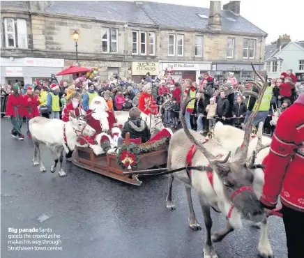  ??  ?? Big paradeSant­a greets the crowd as he makes his way through Strathaven town centre