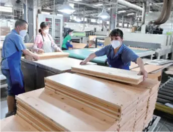  ??  ?? Workers of a company in Fujian Province, southeast China, make wooden components on May 28. While cementing existing overseas orders, the company has also adopted online marketing to expand sales channels