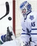  ?? JONATHAN HAYWARD/THE CANADIAN PRESS ?? Leaf goalie Jonathan Bernier eyes the puck as Brad Richardson of the Canucks tumbles into the crease.