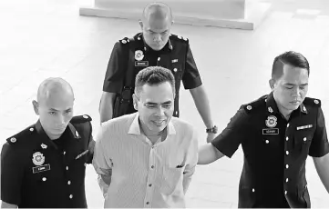  ??  ?? Mohd Adnan (centre) escorted by MACC officers after he pleaded not guilty in the Sessions Court. — Bernama photo