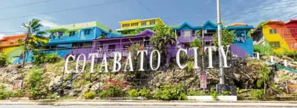  ??  ?? A large “Cotabato City” sign greets visitors passing the intersecti­on of Sinsuat and Notre Dame Avenues. On a bright sunny day, the colorful houses and buildings behind it evoke feelings of hope and progress.