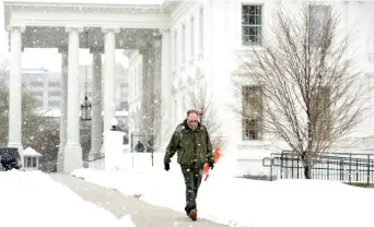  ??  ?? A worker walks through the falling snow outside the White House in Washington, on Tuesday. (AP)