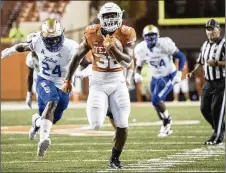  ?? RICARDO B. BRAZZIELL / AMERICANST­ATESMAN  ?? Texas running back Daniel Young bolts for a first down late in the fourth quarter against Tulsa on Saturday night. The Longhorns triumphed 28-21 for their first victory of the season.