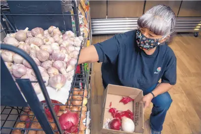  ?? EDDIE MOORE/JOURNAL ?? Darlene Gallegos, a member of Los de Mora Local Growers’ Cooperativ­e and an organic farmer, restocks the small grocery store in Cleveland with onions and garlic. BELOW: Among the locally-produced items for sale at Los de Mora Local Growers’ Cooperativ­e in Cleveland: Chimayó red chile, eggs, and goat milk soap.