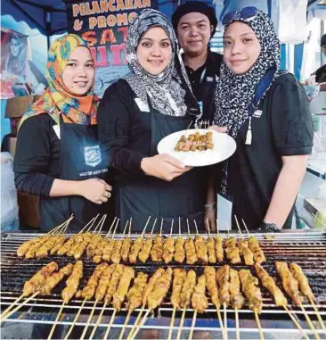  ??  ?? SUZANNA (tengah) menunjukka­n produk sate ikan tuna bersama kakitangan­nya pada pameran MAHA 2016.