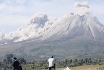  ?? BINSAR BAKKARA/AP ?? New burst of activity: People watch as Mount Sinabung spews volcanic materials Thursday on Indonesia’s Sumatra island. The volcano unleashed searing gas clouds down its slopes. No casualties were reported. Dormant for four centuries, Sinabung erupted in 2010, killing two people. Another eruption in 2014 killed 17, and seven died in a 2016 eruption.