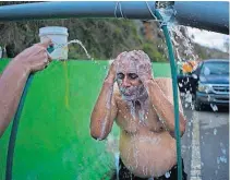  ?? PHOTO] [AP ?? People affected by Hurricane Maria bathe in water piped from a creek in the mountains Thursday in Naranjito, Puerto Rico. Residents of the area drive to the pipes to bathe because they were left without water supplies due to the damage caused by...