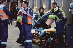  ?? EPA PIC ?? A woman being placed on a gurney by paramedics in Sydney yesterday.