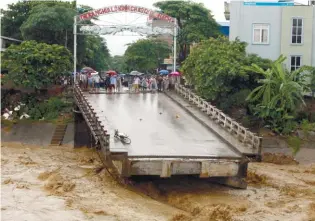  ?? AFPPIX ?? ... This picture from the Vietnam News Agency taken on Wednesday shows residents standing at an end of a destroyed bridge in the northern province of Yen Bai. At least 37 people have died and another 40 are missing after floods and landslides ravaged...