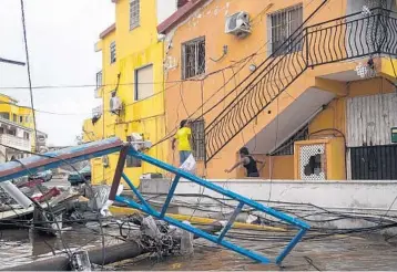  ?? LIONEL CHAMOISEAU/AFP ?? People walk over debris Thursday on Saint Martin, an island divided between the Netherland­s and France.