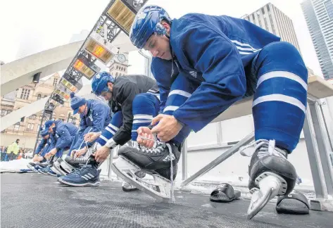  ?? CP PHOTO ?? Toronto Maple Leafs’ Mitch Marner, from left, Auston Matthews and Mike Babcock put on their skates for the team’s outdoor practice at Nathan Phillips Square in front of City Hall in Toronto on Thursday.