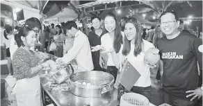  ??  ?? CUBA: Liau (tengah) bersama Vivian (dua kanan) dan Teo (kanan) mencuba makanan di salah sebuah booth.