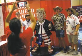  ?? Joe Raedle / Getty Images ?? Attendees of the Conservati­ve Political Action Conference pose for photos with a golden statue of former President Donald Trump on display in Orlando.