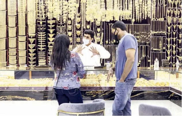  ??  ?? ↑
A salesman speaks to customers in a jewellery store in the Gold Souk in Deira, Dubai.