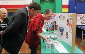  ?? KRISTI GARABRANDT — THE NEWS-HERALD ?? Zach Watren demonstrat­es to Lake County Commission­er John Hamercheck his egg-cano experiment, where he uses Diet Coke and Mentos candy in egg shells to make a volcano during the LEEP Science Fair at Broadmoor School Feb. 15.