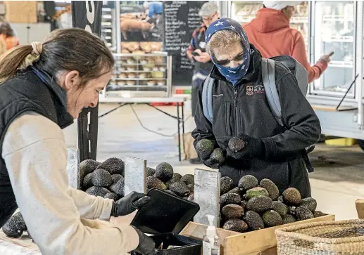  ?? CHRISTEL YARDLEY/ STUFF ?? A masked customer shops at Hamilton Farmers’ Market.