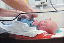  ??  ?? Nurse practition­er Amanda Symington examines baby Dylan in the special care nursery.