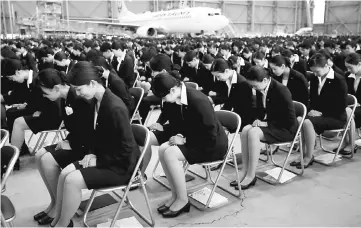  ??  ?? Newly-hired employees of JAL group bow during an initiation ceremony at a hangar of Haneda airport in Tokyo, Japan. At JAL, about 1,100 cabin attendants on contracts were offered permanent full-time jobs last year, following a similar move by its...