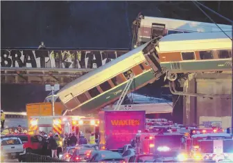  ?? AP PHOTOS ?? DERAILED: Emergency services respond after an Amtrak train derailed onto Interstate 5 near DuPont, Wash., yesterday. A passenger car dangles from the bridge, above.